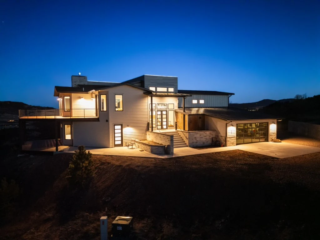 The rear of the house is lit at night beneath a deep blue sky