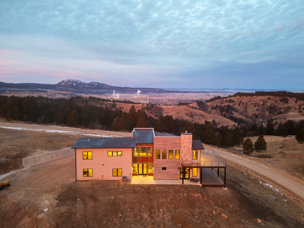An aerial dusk photograph shows the rear of 2111 Vantage Circle glowing against the Black Hills and a distant valley town.