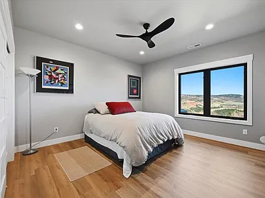 A bedroom features a made bed with red accent pillows