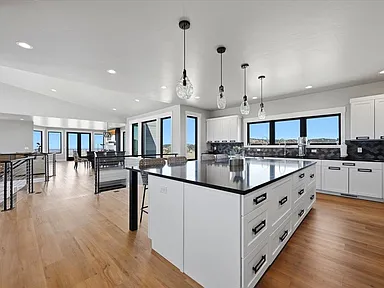 The white kitchen island with pendant lighting is viewed from the dining area