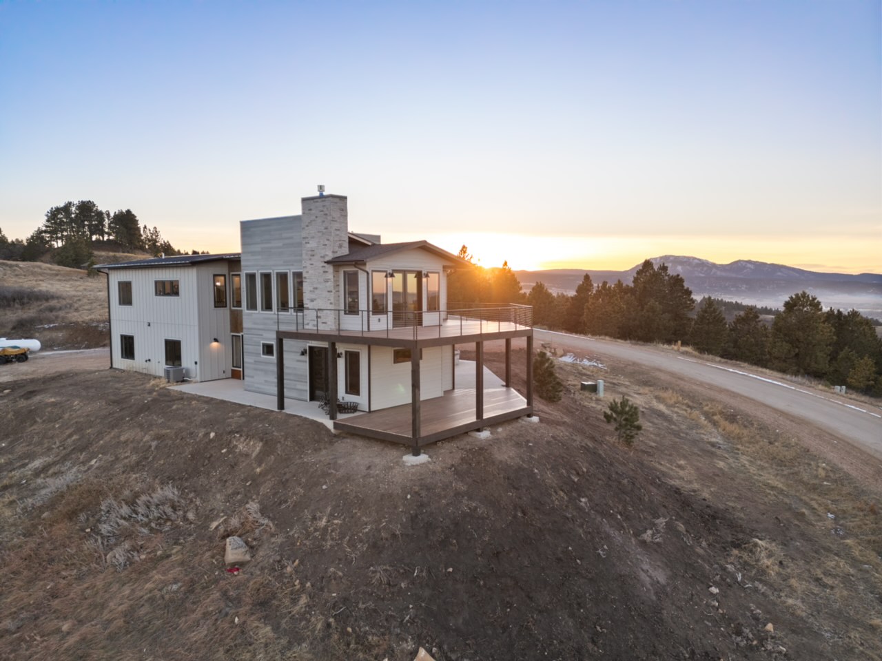 An aerial view at sunrise shows the rear deck and stone chimney