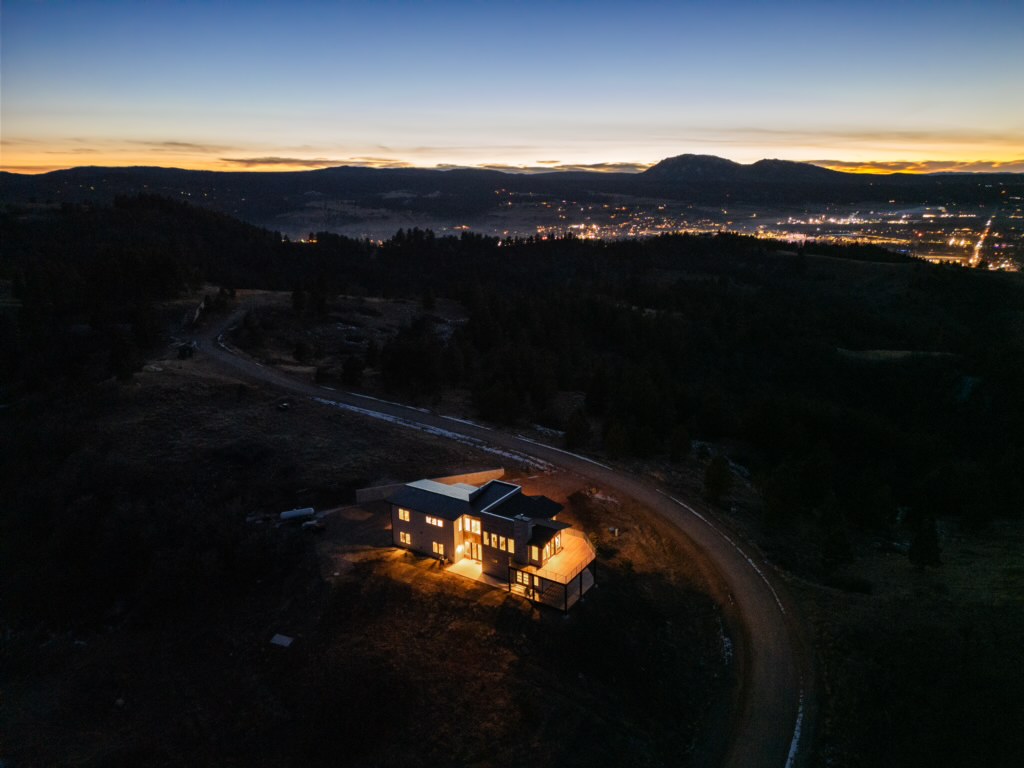 Blue-hour aerial, house lit against the wide horizon