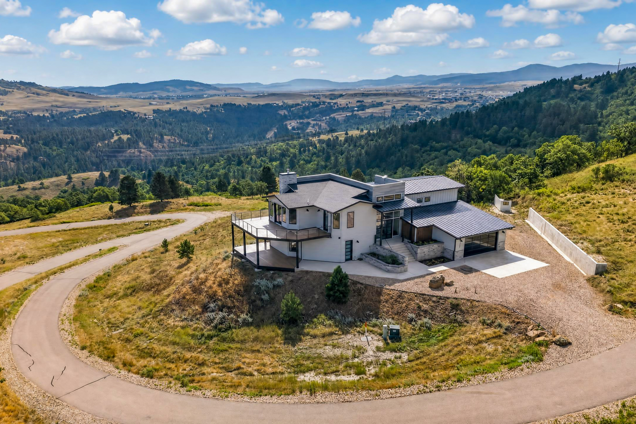 A drone photograph looks past the house toward a hazy valley
