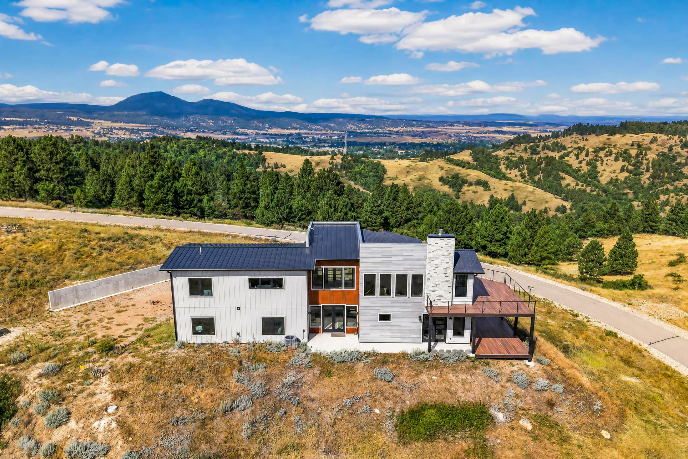 From above, 2111 Vantage Circle is framed by pine-covered hills with a distant mountain range visible on the horizon.
