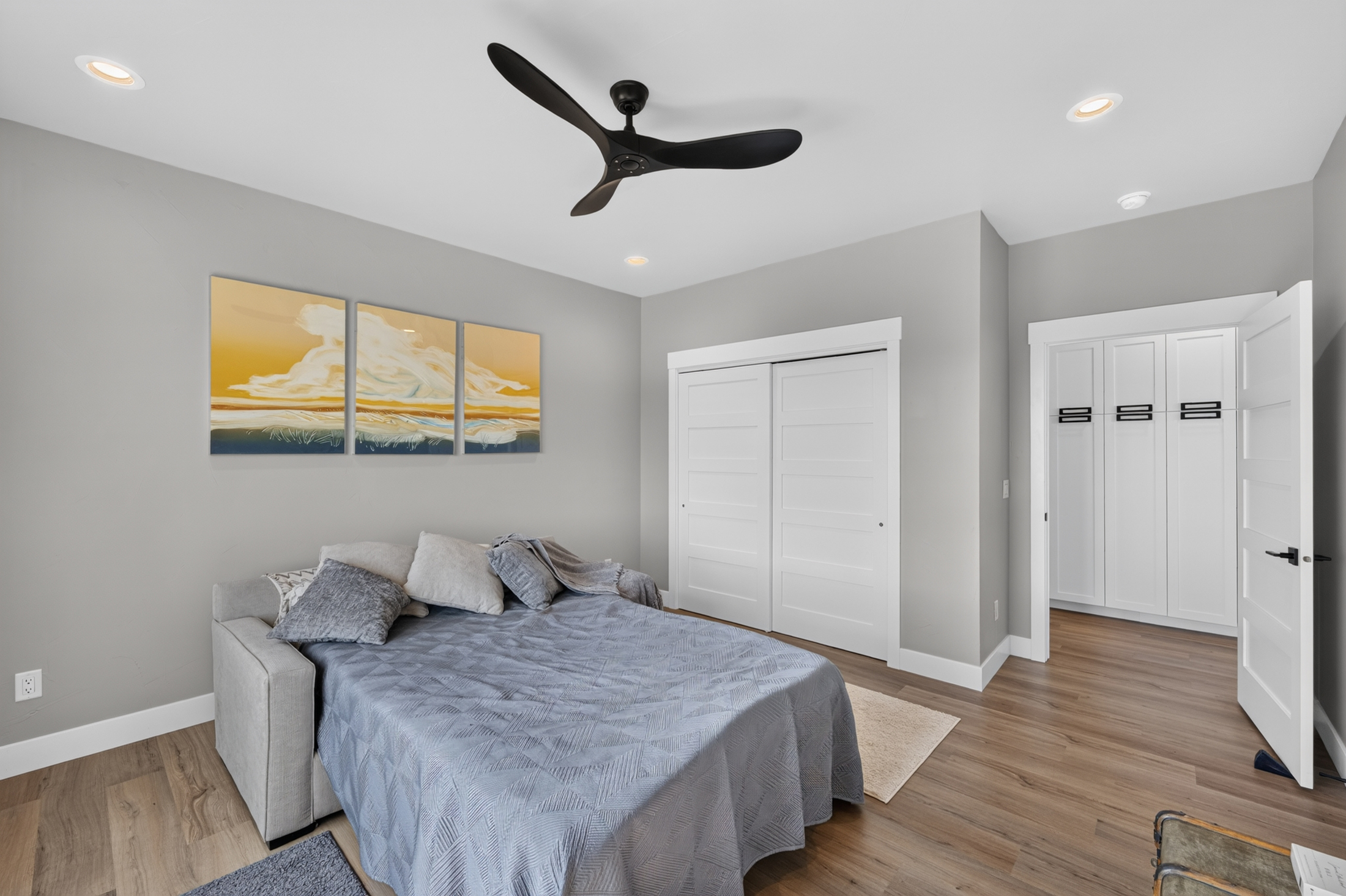 A bedroom with sliding closet doors and a built-in wardrobe opens through a doorway to a hallway beyond.