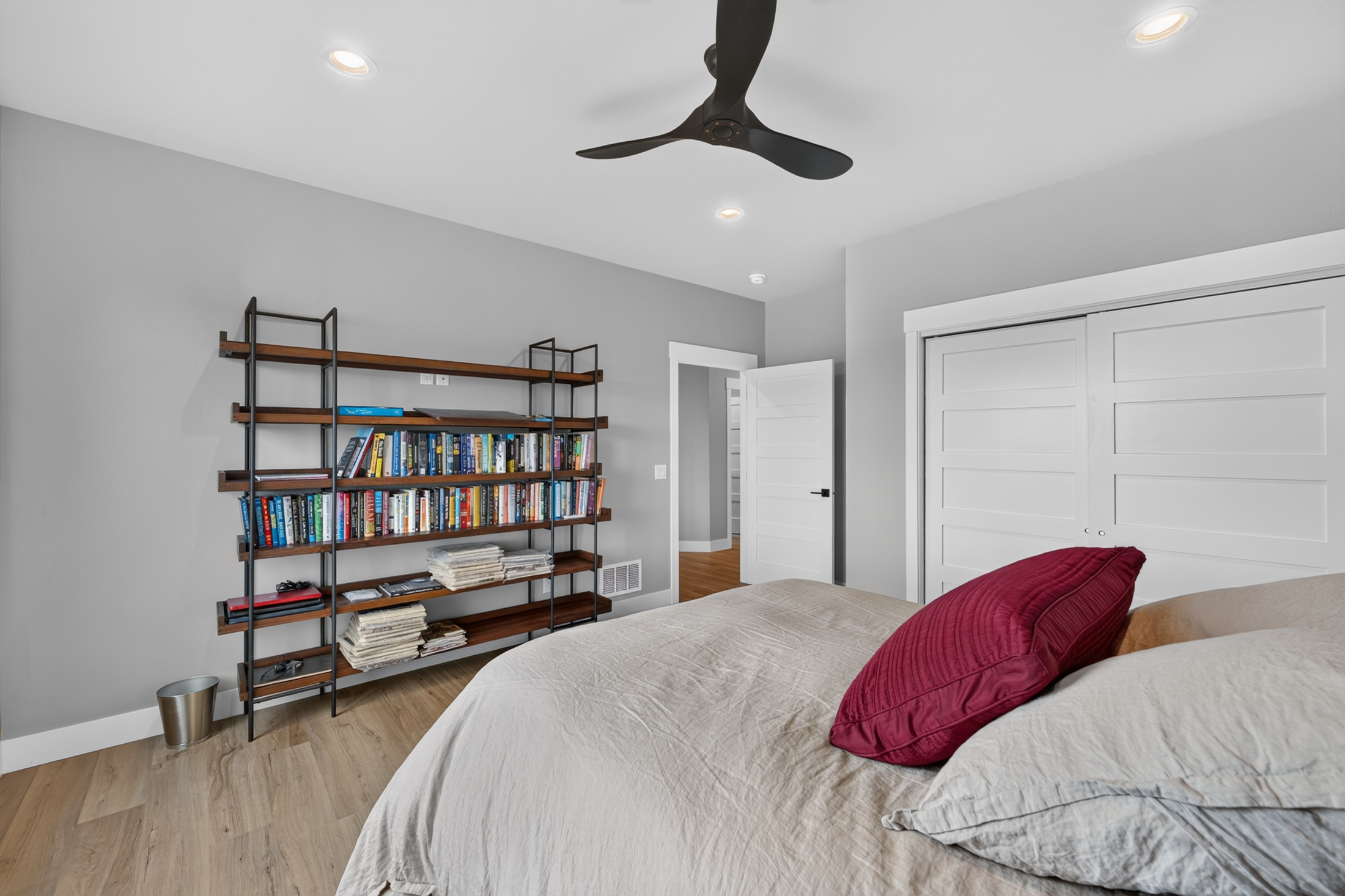 A bedroom at 2111 Vantage Circle with a tall open bookshelf full of books and magazines beside sliding closet doors.