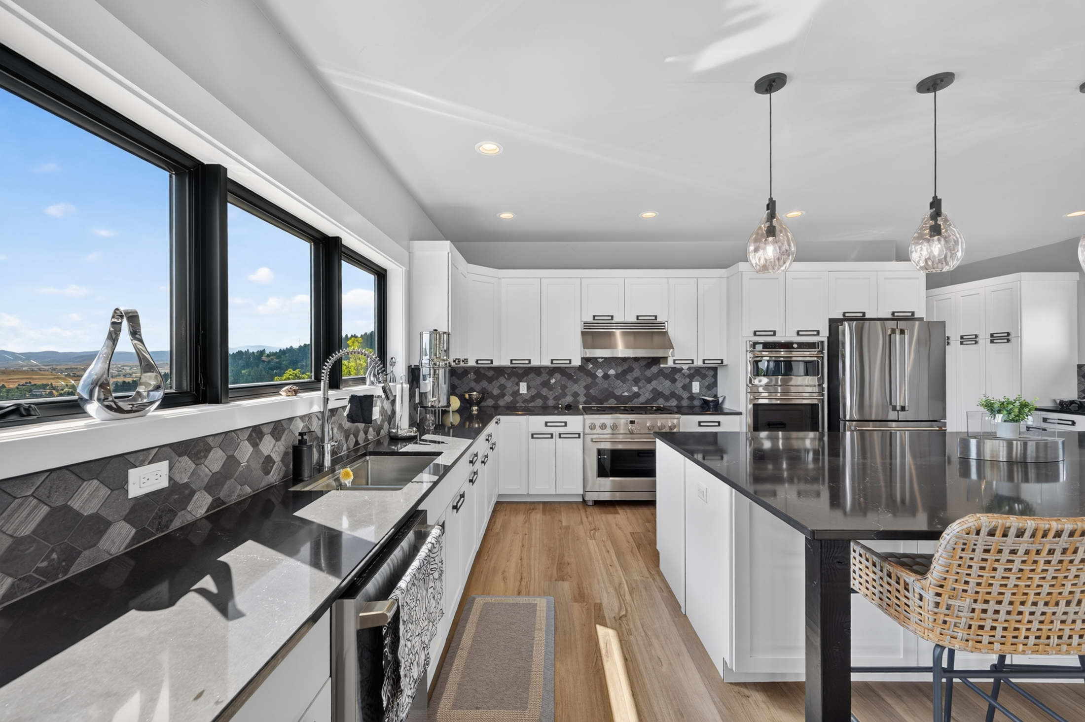 The kitchen's long counter run leads past the range to the island, with a wide window wall bringing in valley light.