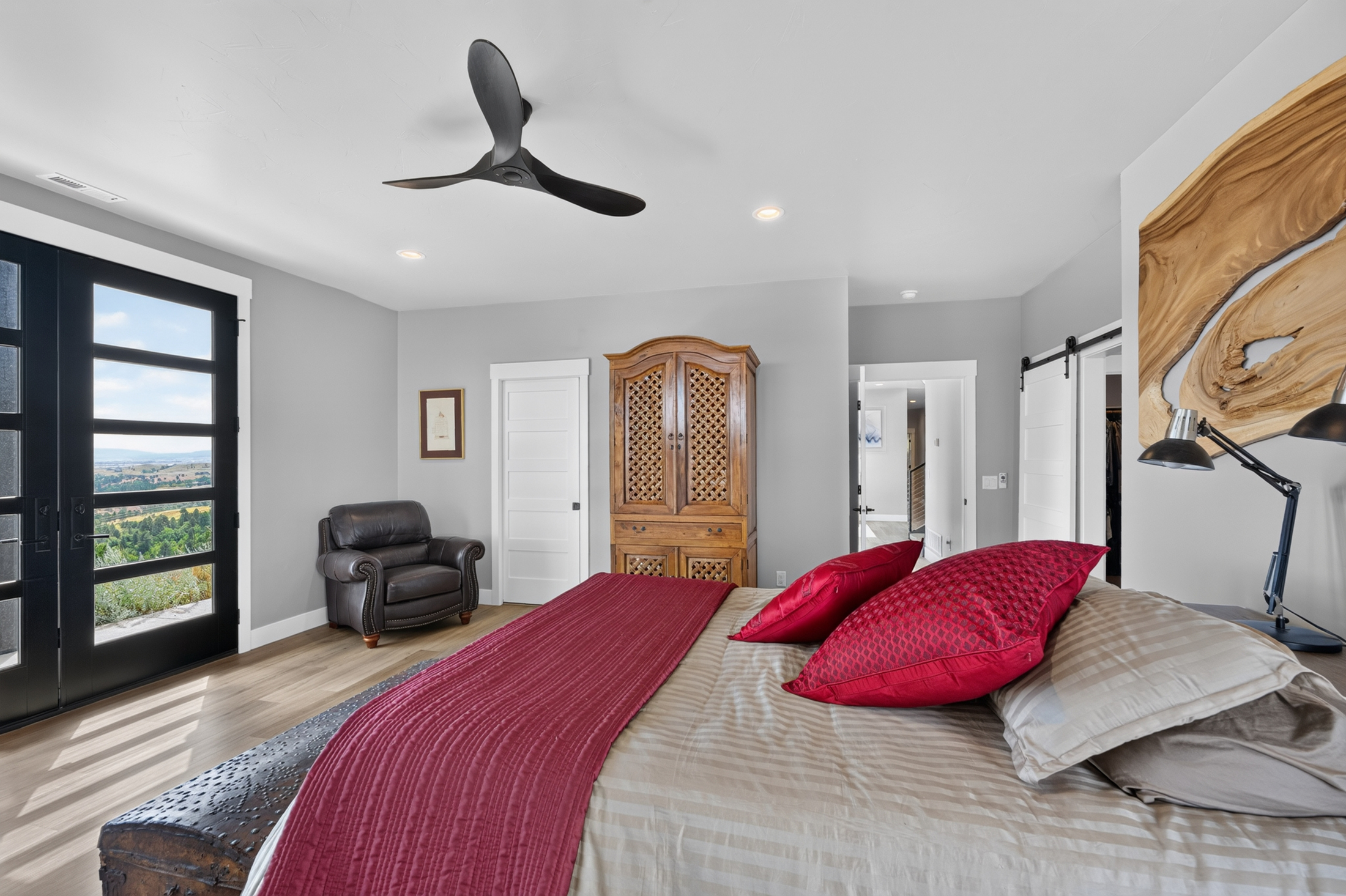 The same guest bedroom seen toward a live-edge wood panel and a sliding barn door leading to a closet at 2111 Vantage Circle.