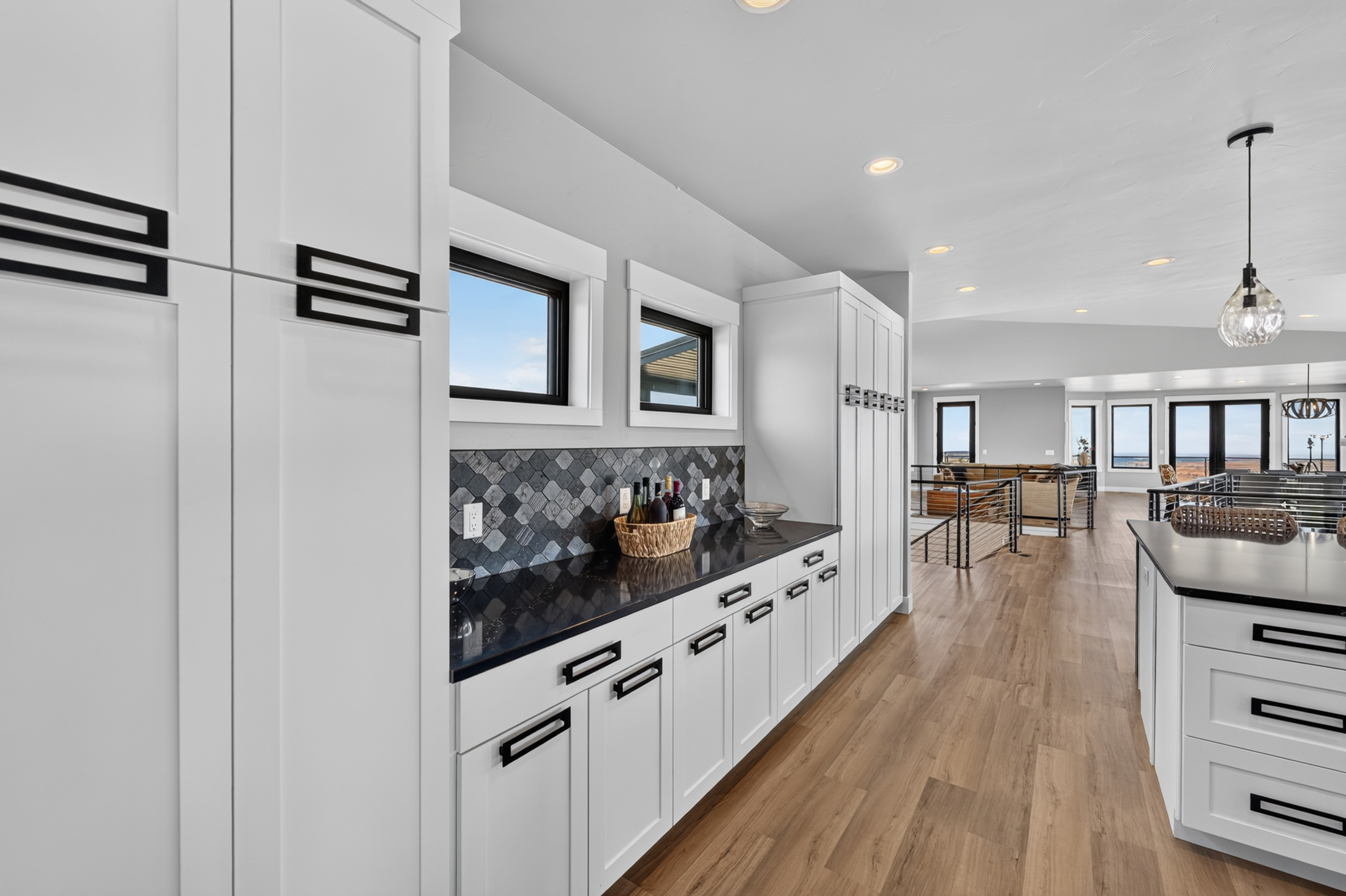 White cabinetry lines a hallway connecting the butler's pantry to the open living room and kitchen island at 2111 Vantage Circle.