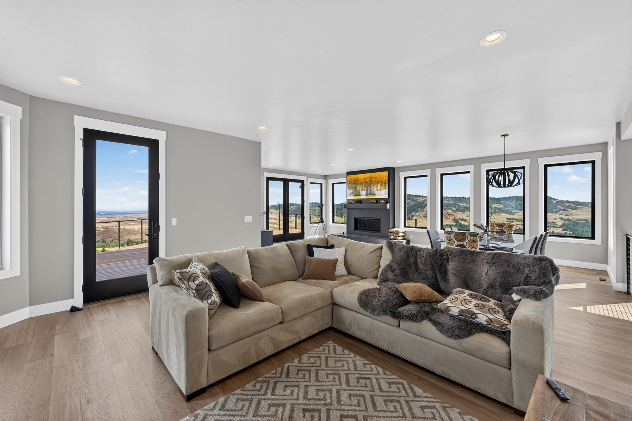 A tan sectional sofa with a fur throw sits near a glass door leading onto the deck at 2111 Vantage Circle.