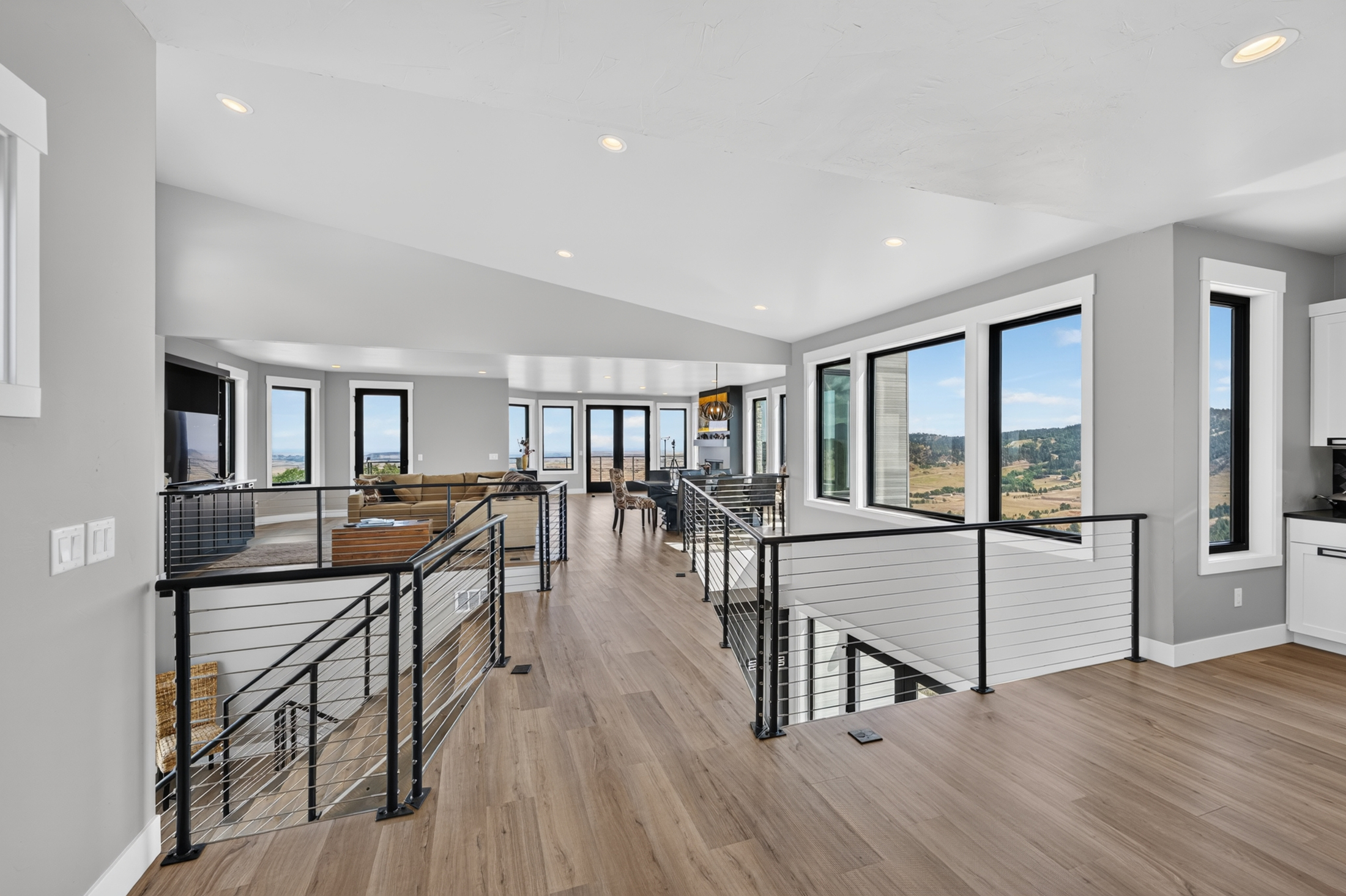 The upper level at 2111 Vantage Circle opens into a great room with wide-plank floors and a wall of windows over the valley.
